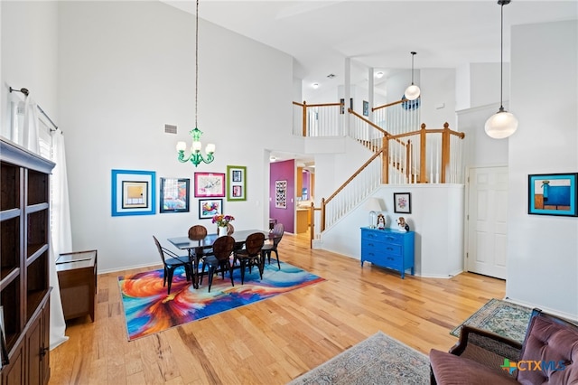 dining space with a chandelier, wood-type flooring, and high vaulted ceiling