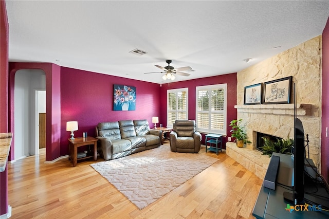 living room featuring a fireplace, hardwood / wood-style floors, a textured ceiling, and ceiling fan