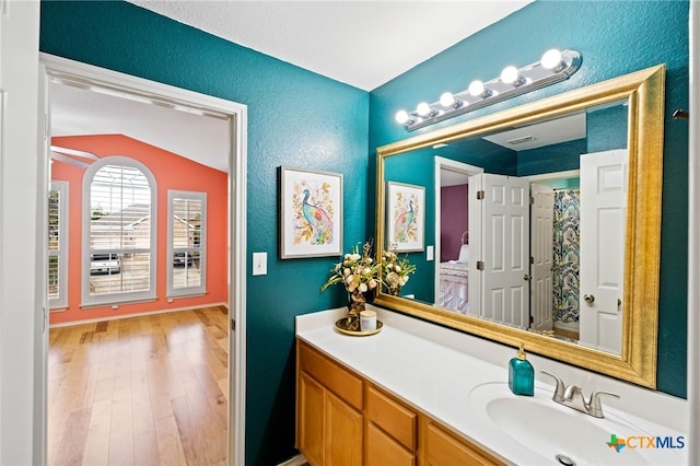 bathroom featuring vanity, hardwood / wood-style flooring, curtained shower, and lofted ceiling