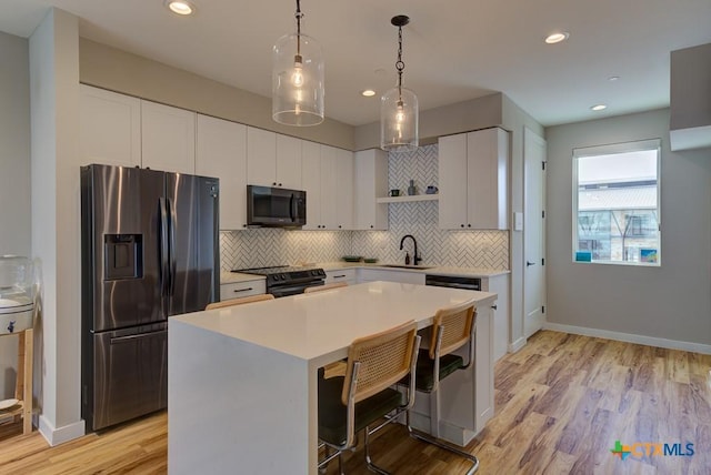 kitchen featuring a breakfast bar, stainless steel refrigerator with ice dispenser, black electric range, white cabinets, and a kitchen island