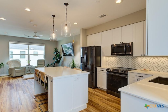 kitchen with electric stove, a center island, white cabinets, and black fridge