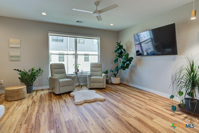 living area featuring light hardwood / wood-style floors and ceiling fan