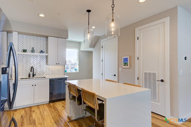 kitchen with sink, decorative light fixtures, black appliances, and white cabinets