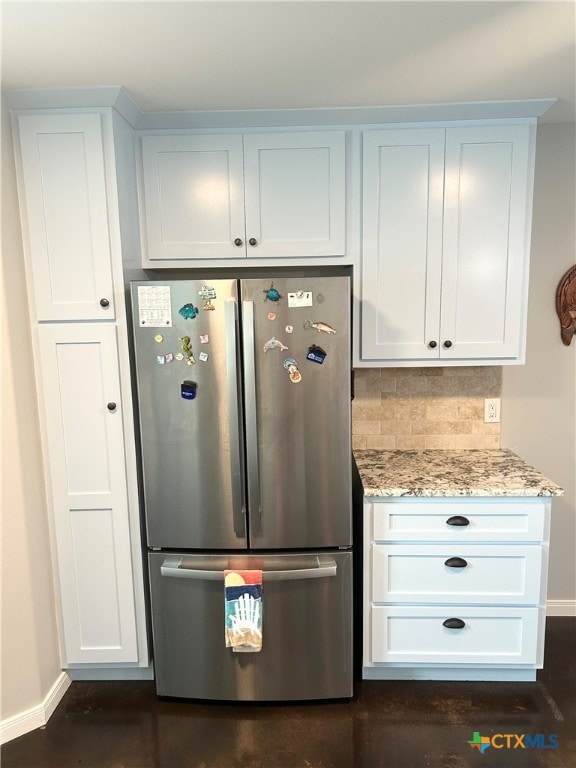 kitchen with stainless steel fridge, white cabinetry, light stone counters, and tasteful backsplash