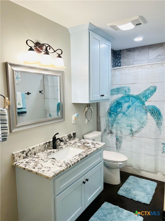 bathroom featuring curtained shower, vanity, and toilet