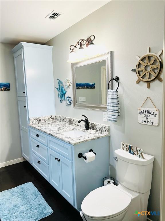 305 W Denver Ave, Seadrift, TX 77983 - bathroom featuring toilet, vanity, baseboards, and wood finished floors