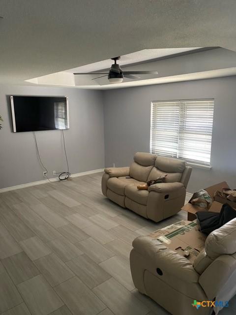 unfurnished living room featuring baseboards and a ceiling fan