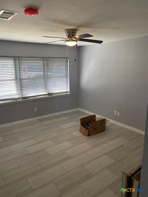 unfurnished room featuring visible vents, baseboards, a healthy amount of sunlight, and ceiling fan