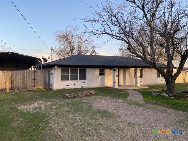 ranch-style house with a carport, a front yard, and fence