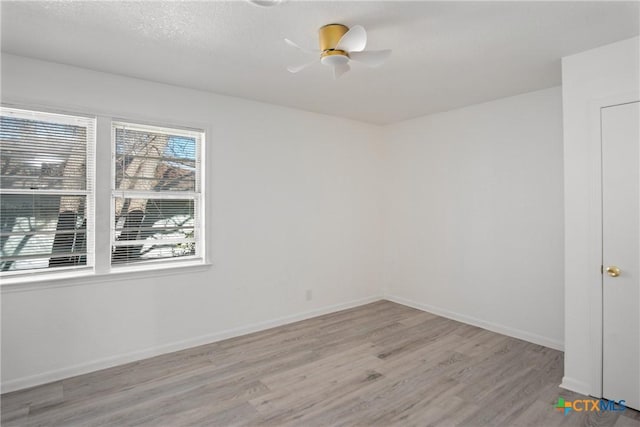 empty room with ceiling fan, light hardwood / wood-style flooring, and a textured ceiling