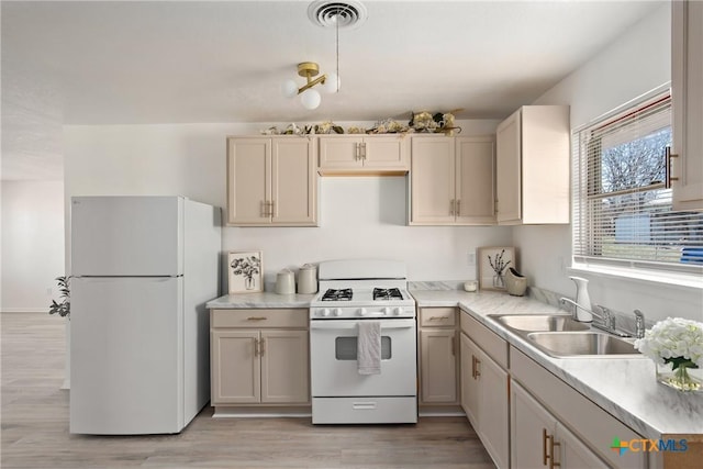 kitchen with sink, light hardwood / wood-style floors, white appliances, and cream cabinetry