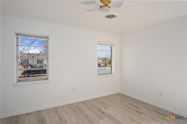 spare room featuring light wood-type flooring, plenty of natural light, and ceiling fan