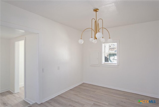 unfurnished dining area featuring light wood-type flooring and an inviting chandelier