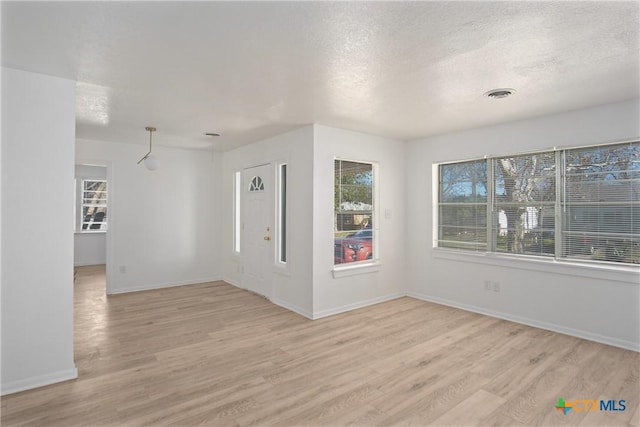 unfurnished room with a textured ceiling and light hardwood / wood-style flooring