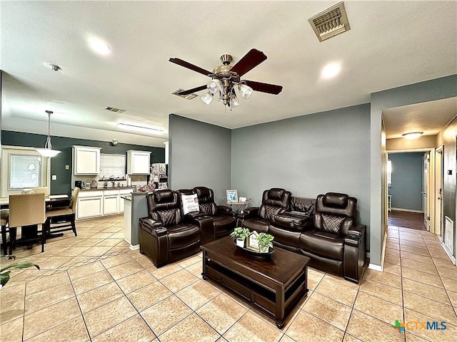 living room with light tile patterned floors, baseboards, visible vents, and a ceiling fan