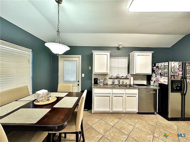 kitchen featuring dishwasher, lofted ceiling, fridge with ice dispenser, white cabinetry, and a sink