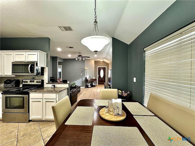 dining space with lofted ceiling, ceiling fan, visible vents, and light tile patterned flooring