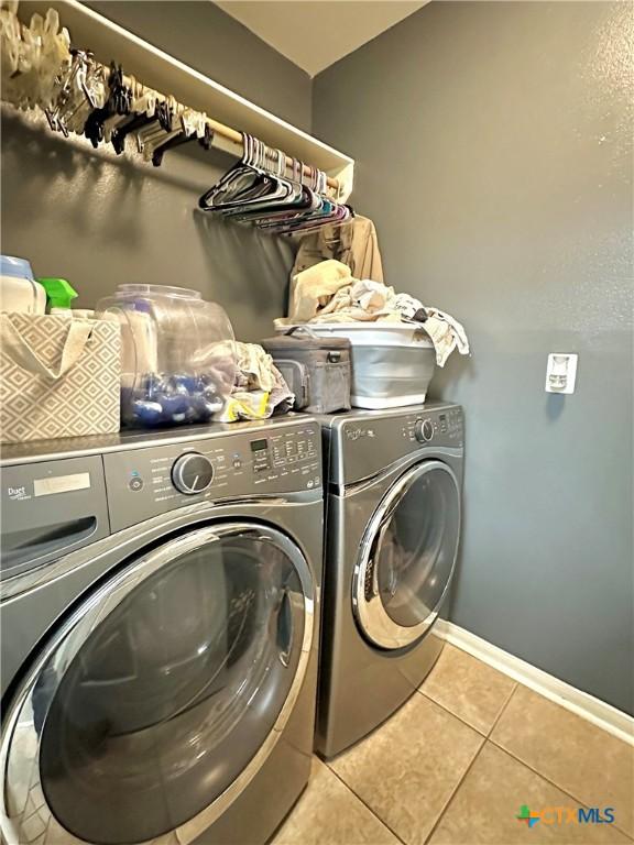 laundry area with laundry area, tile patterned flooring, baseboards, and washer and clothes dryer