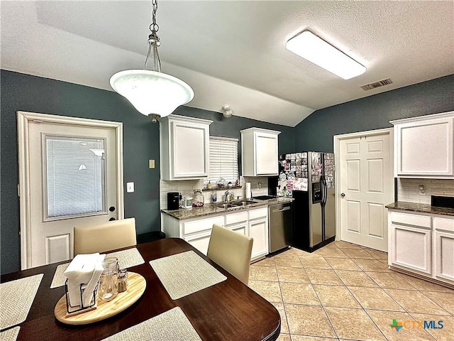 kitchen featuring visible vents, dark countertops, stainless steel dishwasher, white cabinetry, and a sink