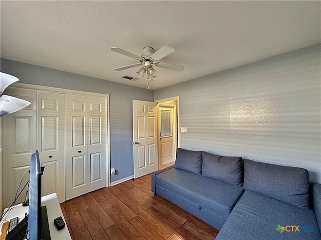 living room with a ceiling fan, dark wood-style flooring, visible vents, and baseboards