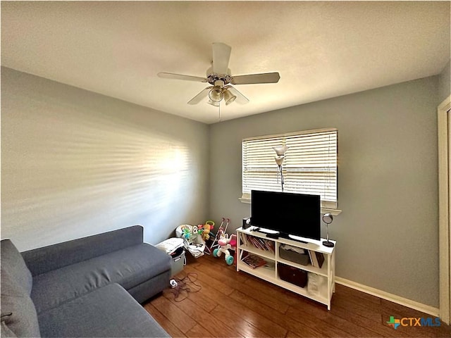 living room with hardwood / wood-style floors, a ceiling fan, and baseboards