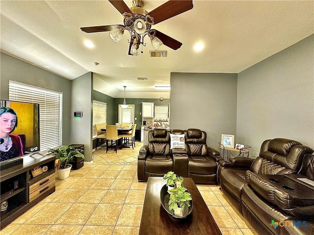 living room featuring light tile patterned floors, ceiling fan, visible vents, and vaulted ceiling