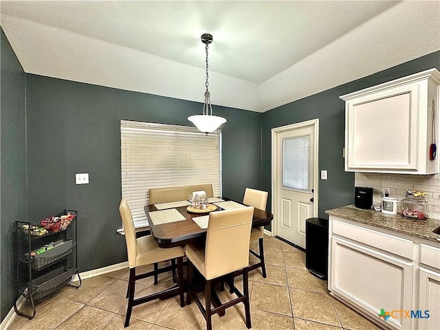 dining space with vaulted ceiling, baseboards, and light tile patterned floors