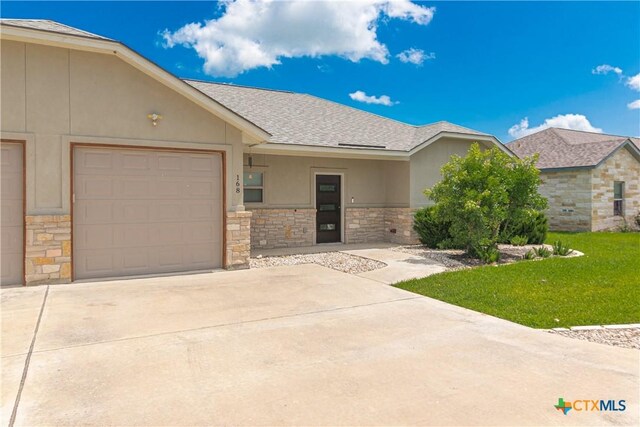 168 Navarro Xing, Seguin, TX 78155 - view of front of house with stone siding, driveway, roof with shingles, an attached garage, and stucco siding