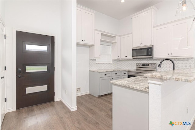 168 Navarro Xing, Seguin, TX 78155 - kitchen with stainless steel appliances, a peninsula, light stone countertops, light wood finished floors, and decorative backsplash