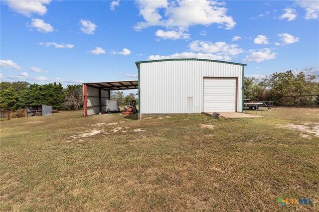 view of outdoor structure with a garage, a yard, and a carport