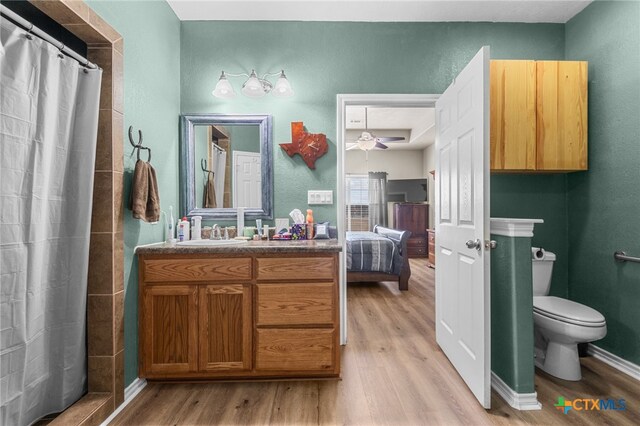 bathroom featuring toilet, hardwood / wood-style floors, vanity, ceiling fan, and a shower with shower curtain