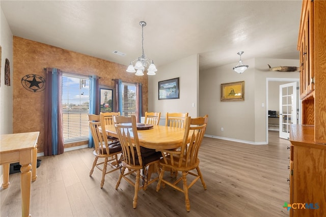 dining space with light wood-type flooring and an inviting chandelier