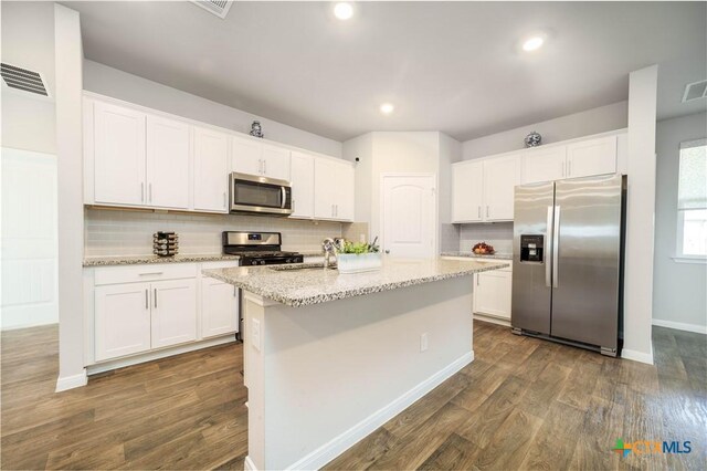 630 Golden Grove Pkwy, San Marcos, TX 78666 - kitchen with visible vents, an island with sink, appliances with stainless steel finishes, dark wood-style floors, and white cabinetry
