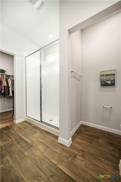 630 Golden Grove Pkwy, San Marcos, TX 78666 - bathroom with visible vents, a shower stall, a walk in closet, baseboards, and wood finished floors