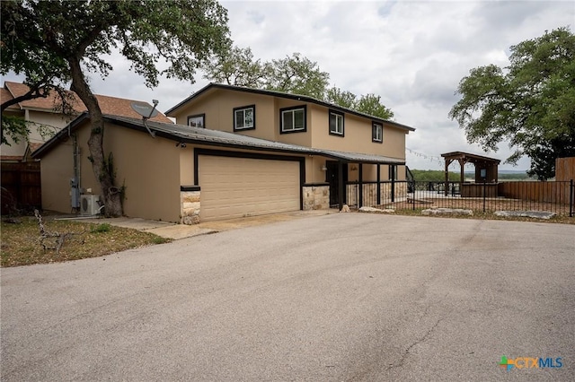 view of front of house with fence, stucco siding, stone siding, and aphalt driveway