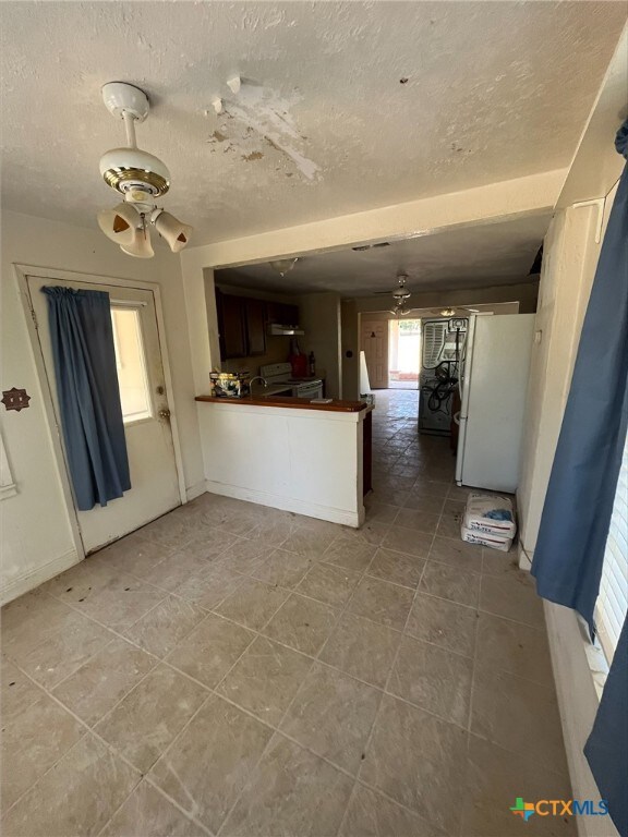 kitchen with white appliances, a textured ceiling, light tile patterned floors, and ceiling fan