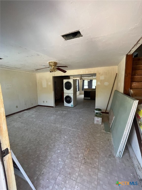 clothes washing area featuring ceiling fan and stacked washer / dryer