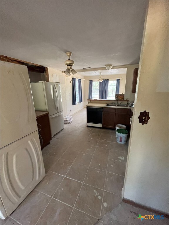 kitchen featuring sink, kitchen peninsula, ceiling fan, white refrigerator, and black dishwasher