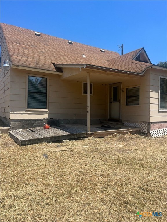 rear view of property featuring a wooden deck and a lawn