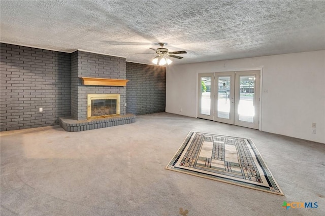 925 Eden Roc St, Victoria, TX 77904 - unfurnished living room featuring carpet, a ceiling fan, a brick fireplace, a textured ceiling, and brick wall
