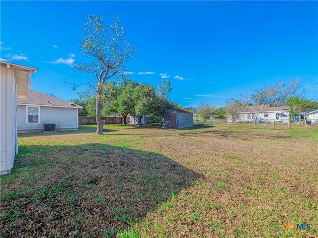 view of yard featuring central AC unit and a storage shed