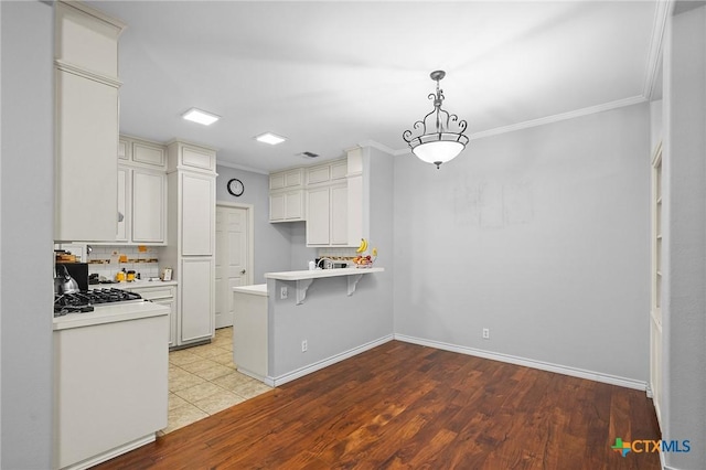 214 Belmoor Ln, Victoria, TX 77904 - kitchen featuring a peninsula, light countertops, ornamental molding, a kitchen bar, and light wood-style floors
