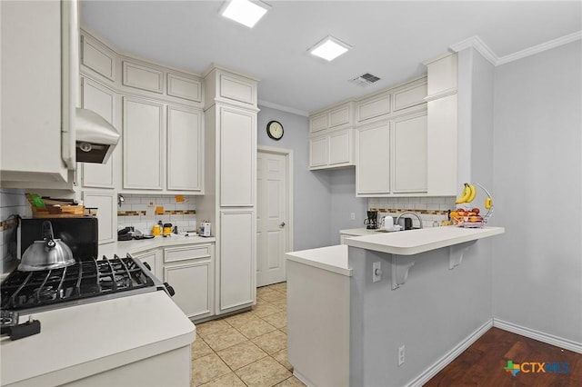 214 Belmoor Ln, Victoria, TX 77904 - kitchen with a peninsula, backsplash, light countertops, ornamental molding, and extractor fan
