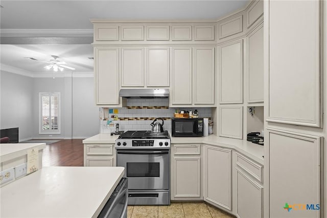 214 Belmoor Ln, Victoria, TX 77904 - kitchen with stainless steel range, ornamental molding, light countertops, under cabinet range hood, and black microwave