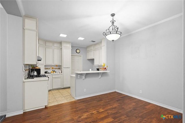 214 Belmoor Ln, Victoria, TX 77904 - kitchen with light wood-style flooring, light countertops, a peninsula, a breakfast bar, and ornamental molding