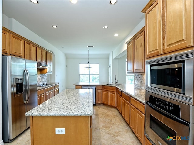 kitchen featuring stainless steel appliances, a kitchen island, decorative light fixtures, sink, and kitchen peninsula