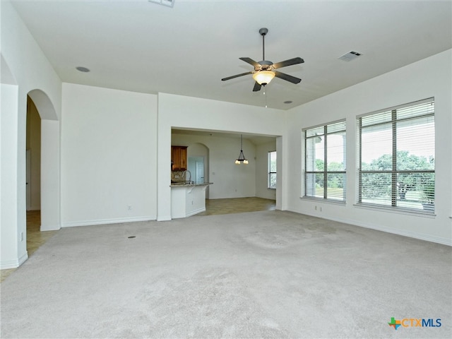 unfurnished living room featuring light carpet and ceiling fan