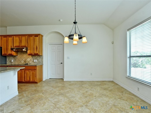 kitchen featuring backsplash, a wealth of natural light, decorative light fixtures, and lofted ceiling