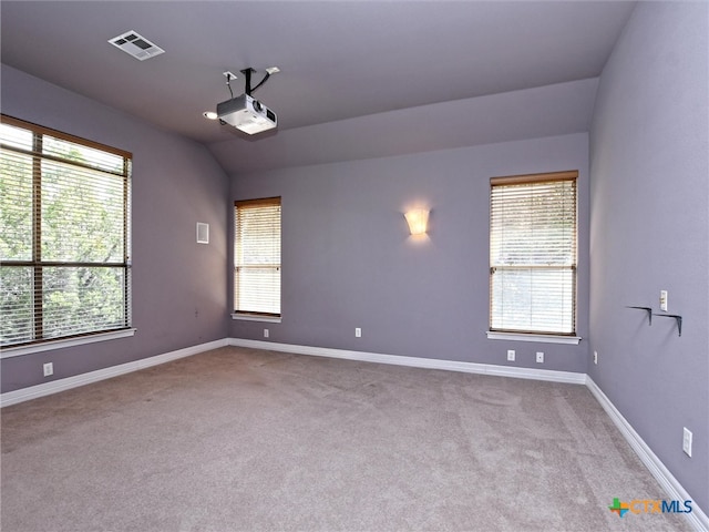 spare room featuring a wealth of natural light, light carpet, and lofted ceiling