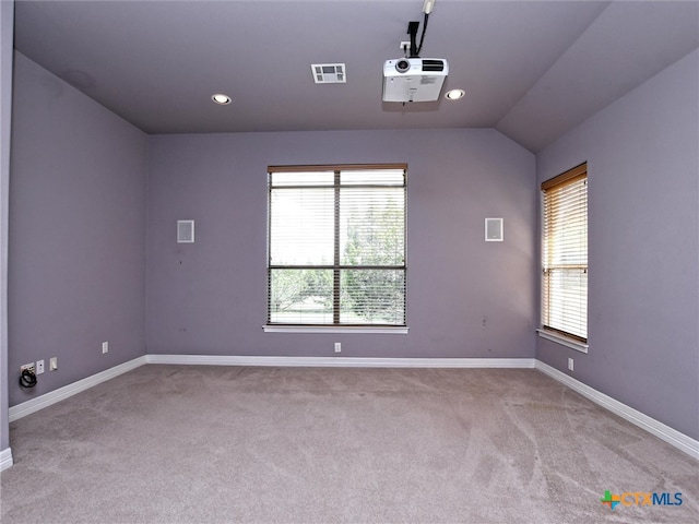 carpeted spare room featuring a wealth of natural light and vaulted ceiling